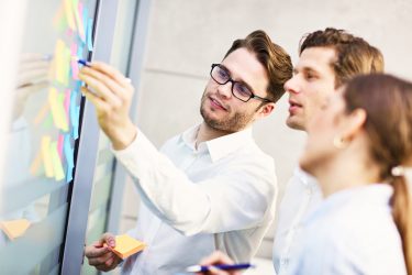 gruppe-von-geschaftsleuten-die-ideen-im-modernen-buro-teilen